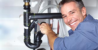 Male plumber fixes pipe under sink