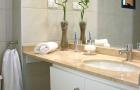 earth tone bathroom counter top with white towels and bamboo in stone-filled vase