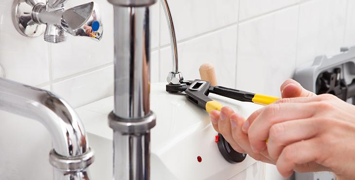 man fixes bathroom sink pipe with a wrench